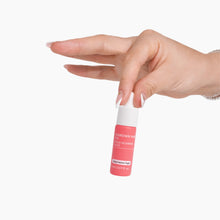 Load image into Gallery viewer, Hand holding a pink lip balm with a white cap on a white background
